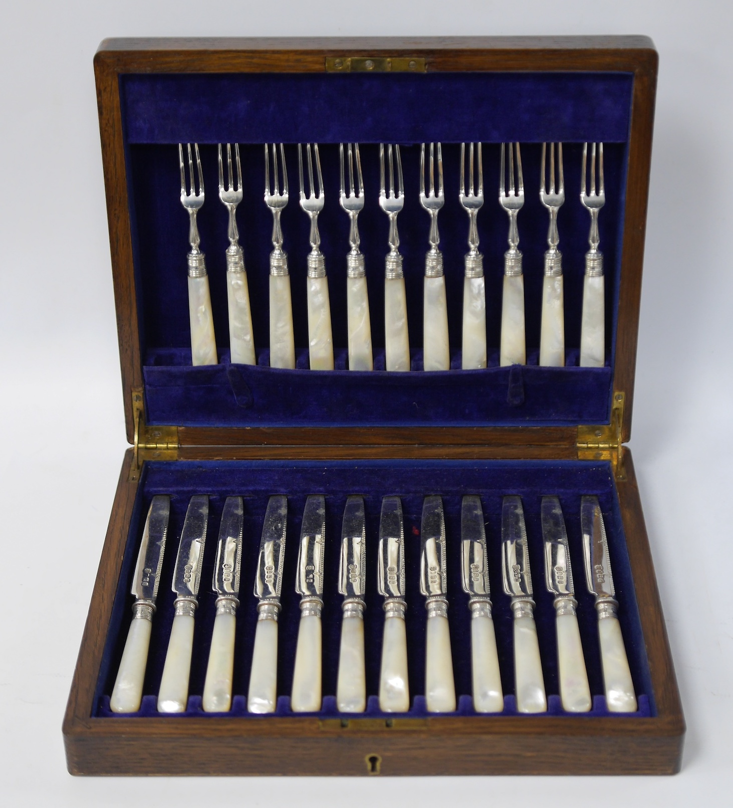 Twelve George V mother of pearl handled silver dessert eaters and eleven matching dessert forks, Barker Brothers Silver Ltd, Birmingham, 1930, knife 18.5cm, housed in a fitted mahogany canteen. Condition - fair to good